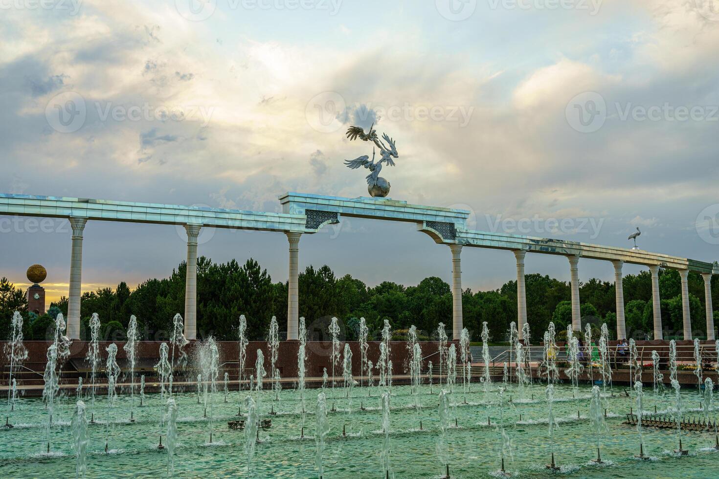 monumento y filas de fuentes iluminado por luz de sol a puesta de sol o amanecer en el independencia cuadrado a Hora de verano, Taskent. foto