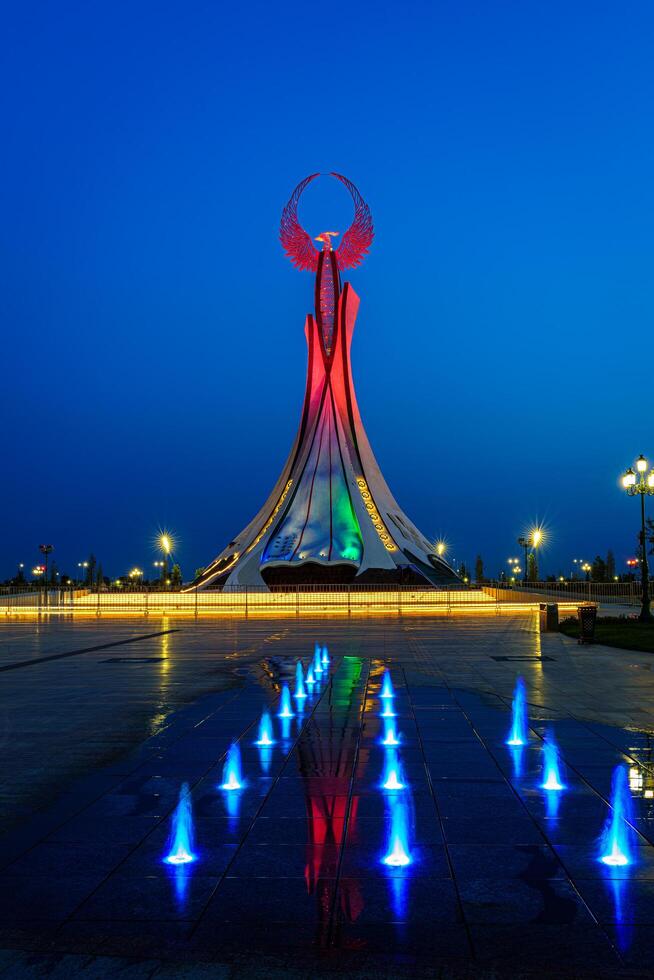 UZBEKISTAN, TASHKENT - MAY 25, 2023 Illuminated monument of independence in the form of a stele with a Humo bird and fountains in the New Uzbekistan park at nighttime. photo