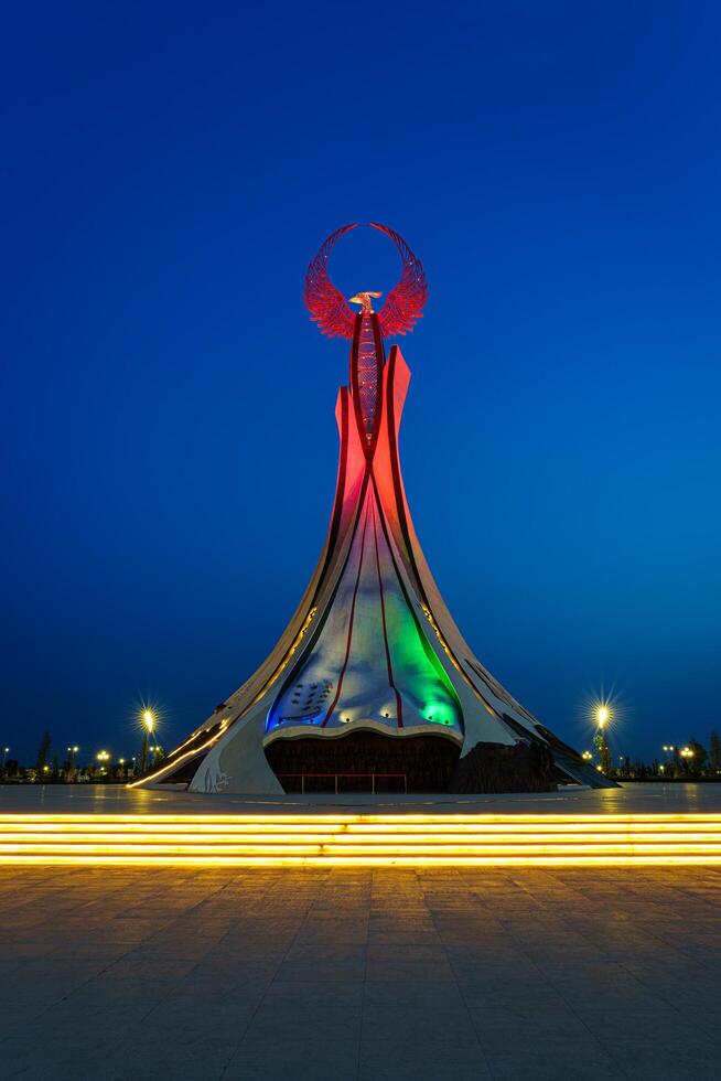 UZBEKISTAN, TASHKENT - MAY 25, 2023 Illuminated monument of independence in the form of a stele with a Humo bird in the New Uzbekistan park at nighttime. photo