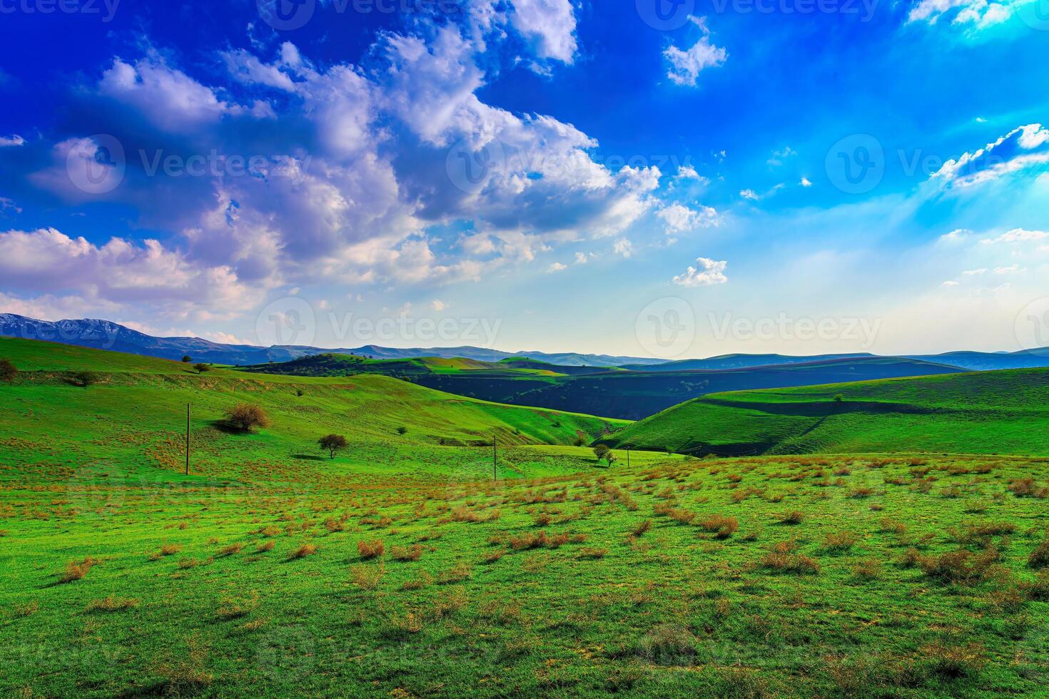 Hills and mountains covered with young green grass and illuminated by the sun on a sunny day. photo