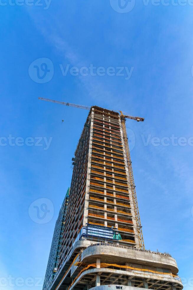 A crane building a skyscraper against a blue sky. photo