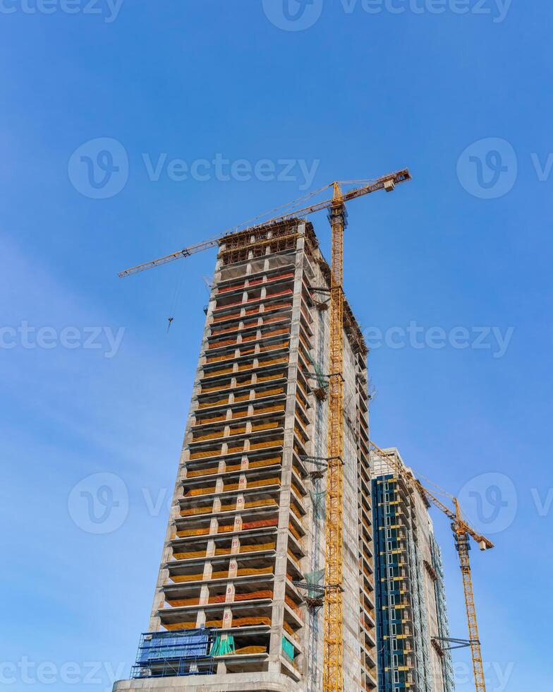 A crane building a skyscraper against a blue sky. photo