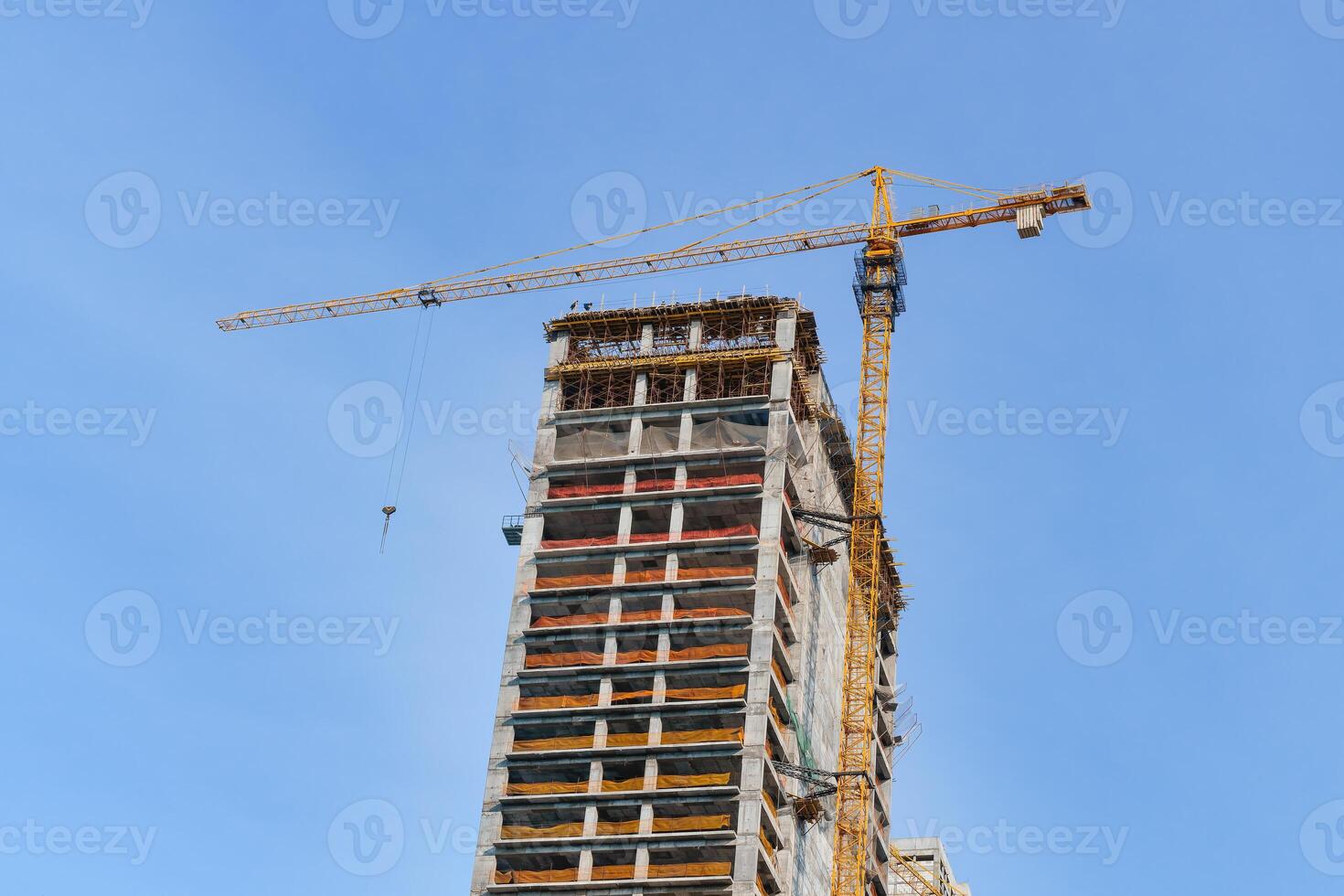 A crane building a skyscraper against a blue sky. photo