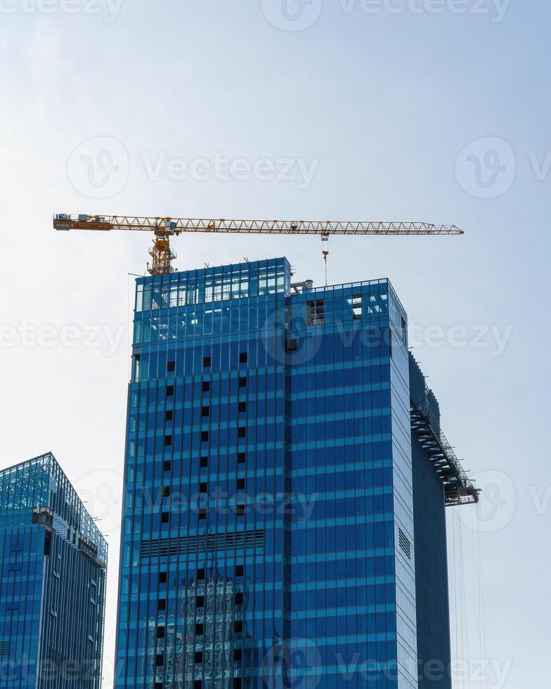 A crane building a skyscraper against a blue sky. photo