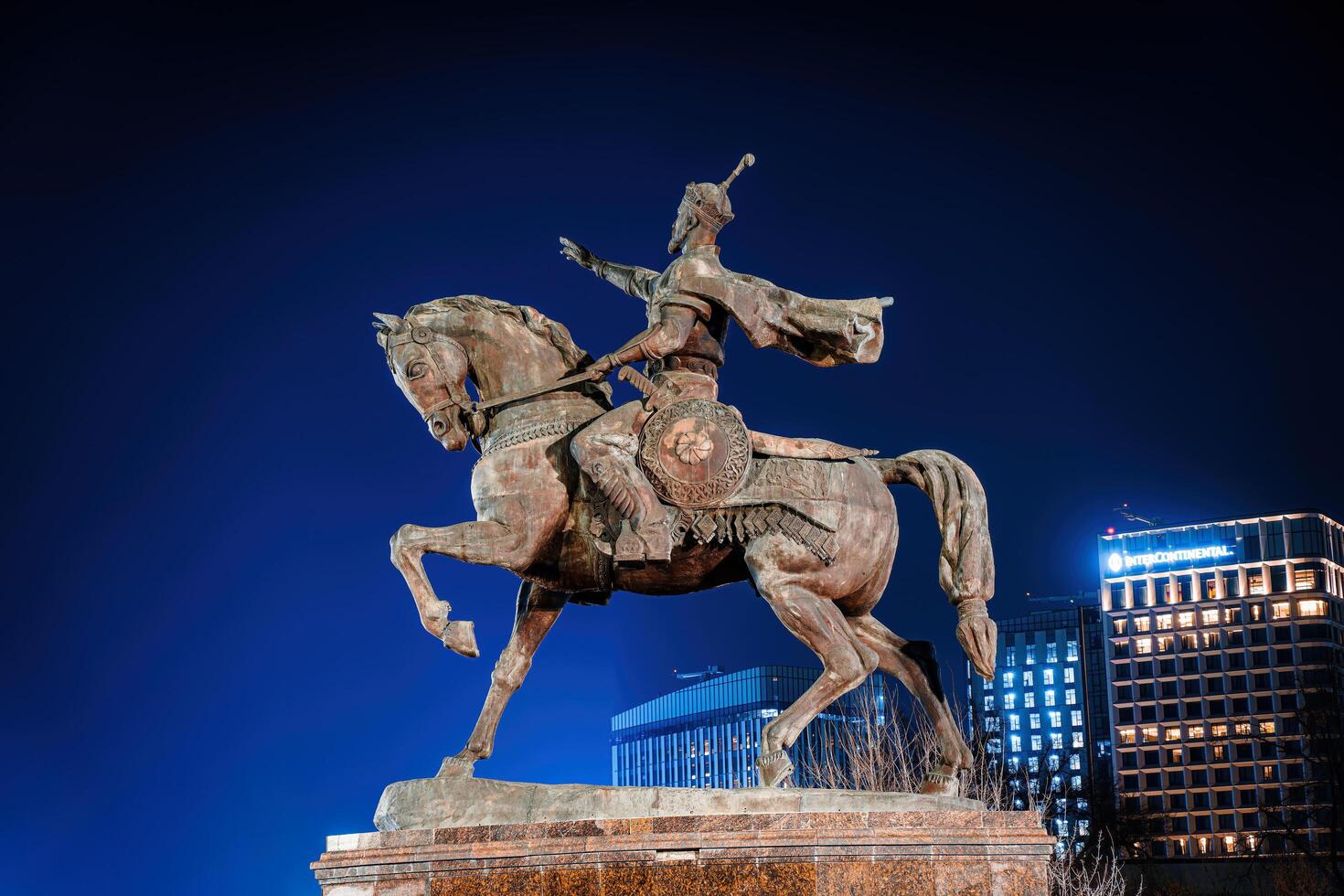 TASHKENT, UZBEKISTAN - MARCH 14, 2023 Monument Amir Timur or Tamerlane at nighttime against the backdrop of the hotel. photo