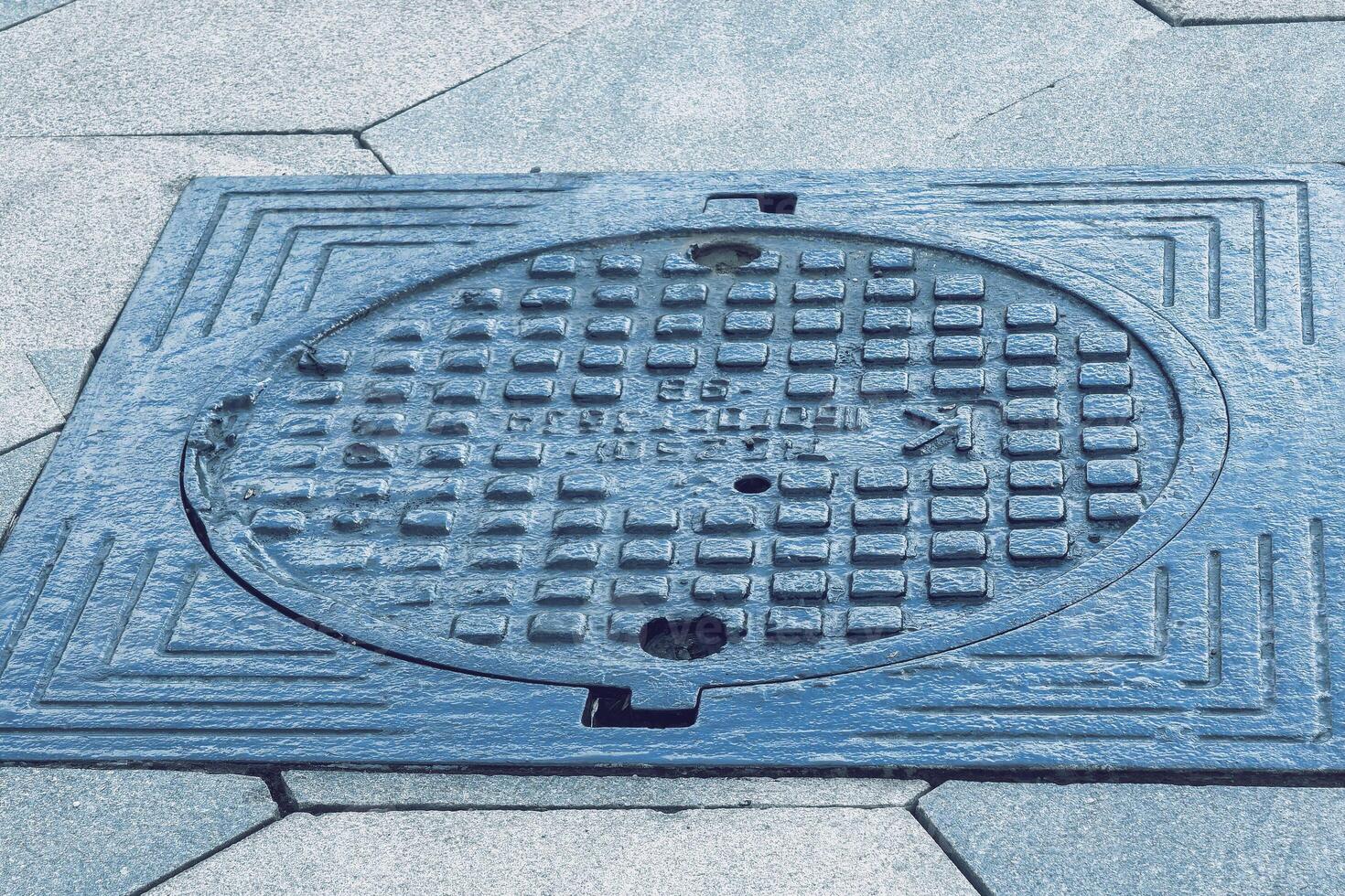 The cover of a sewer manhole on the pavement. photo