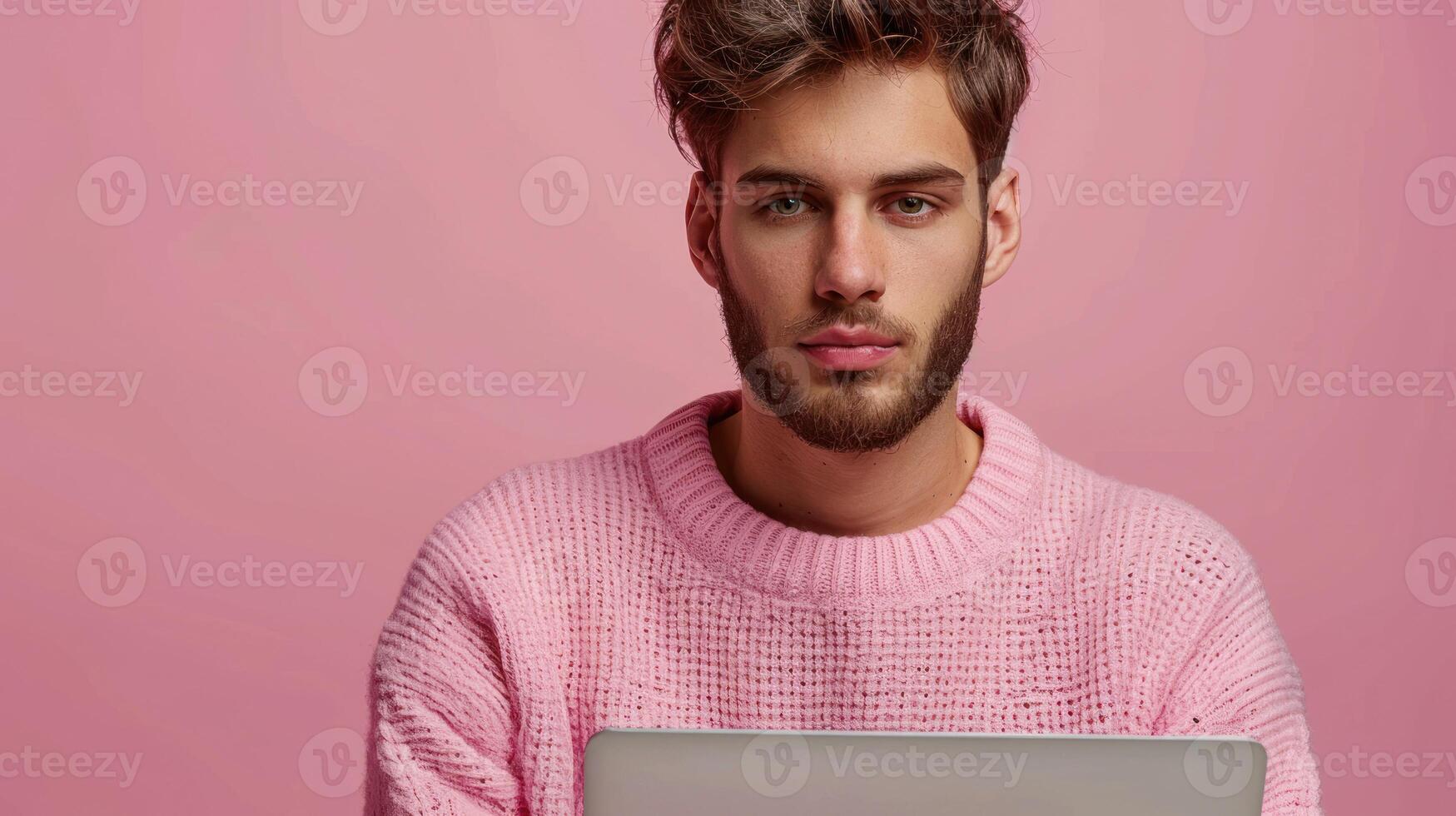 A man wearing a pink sweater holding a laptop photo