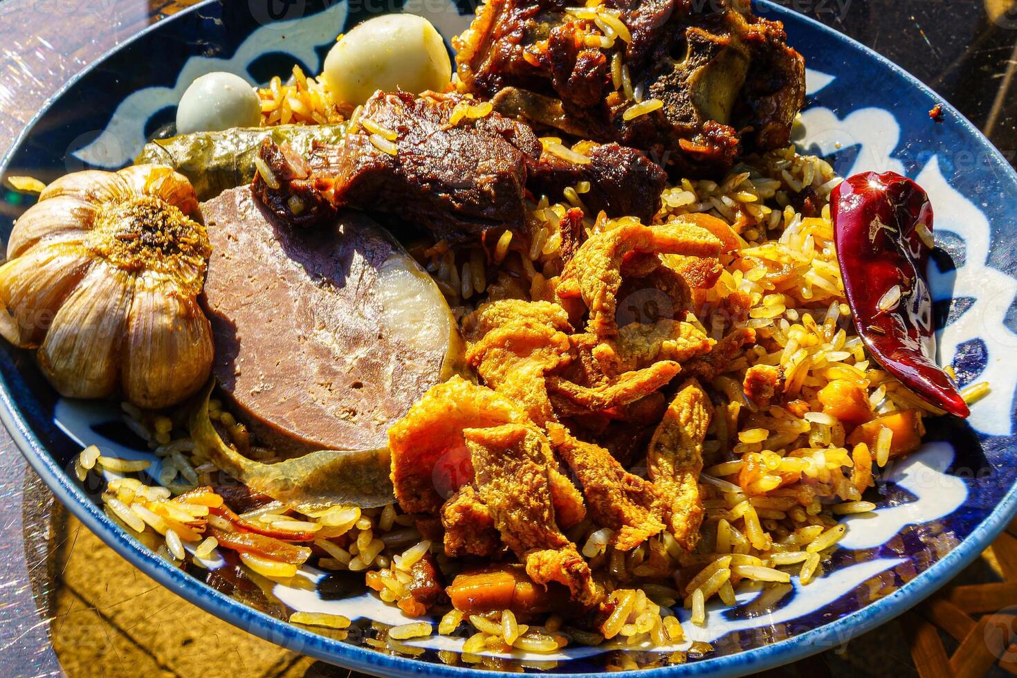 Top view of a plate with Uzbek oriental pilaf with pieces of lamb, horse meat, quail rice and chicken egg. Asian cuisine. photo