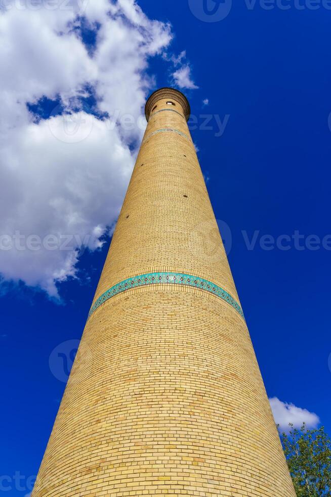 The minaret of a brick mosque against a cloudy sky. photo