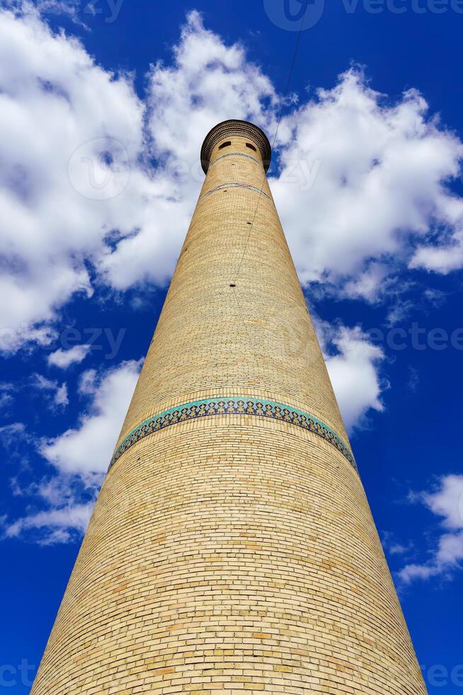The minaret of a brick mosque against a cloudy sky. photo