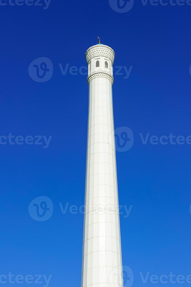 el alminar de el menor mezquita es hecho de blanco mármol en contra un azul cielo. foto
