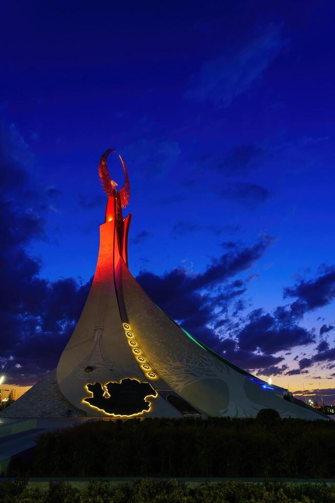 Uzbekistan, Tashkent - October 4, 2023 Illuminated monument of independence in the form of a stele with a Humo bird in the New Uzbekistan park at nighttime in autumn. photo