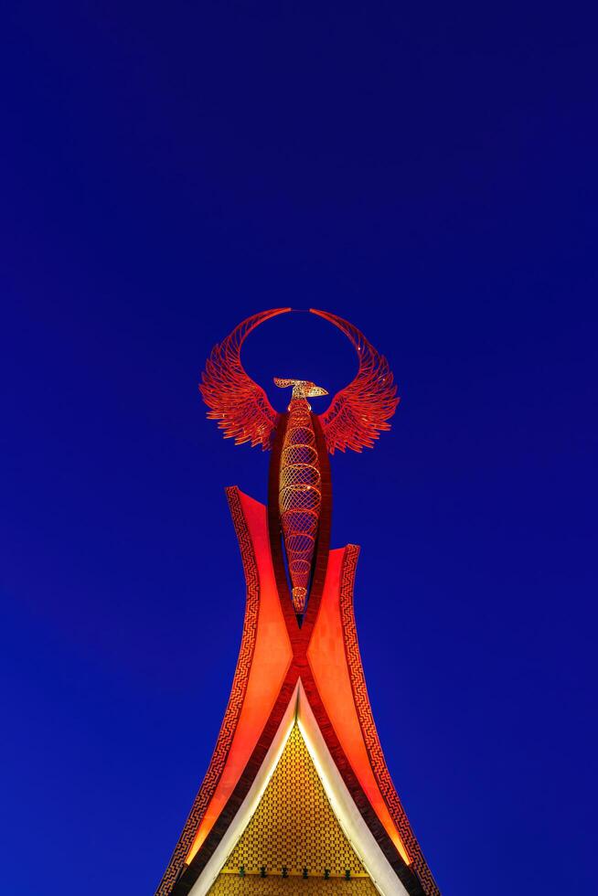 Uzbekistan, Tashkent - October 4, 2023 Illuminated monument of independence in the form of a stele with a Humo bird in the New Uzbekistan park at nighttime in autumn. photo