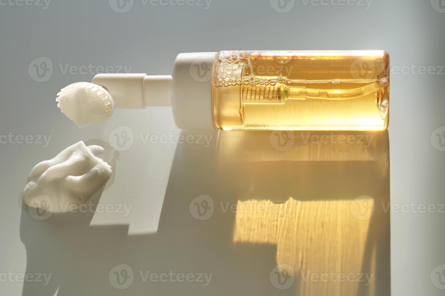 Beige facial foam with a dispenser and brush in the rays of the setting sun. photo