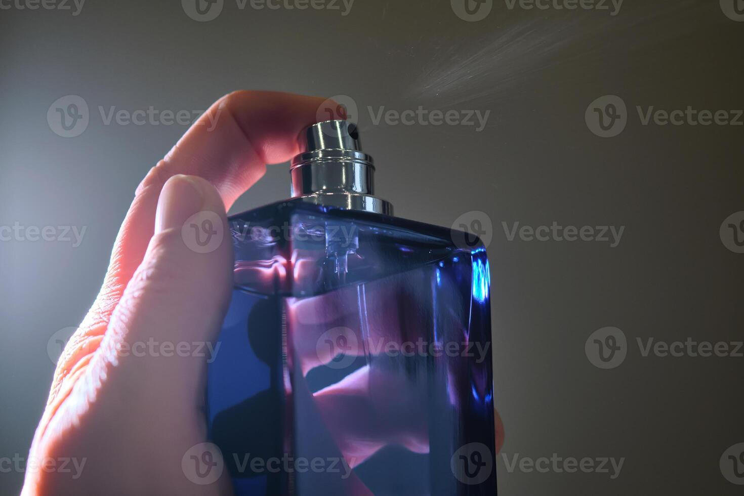 perfume rociar en un Violeta botella en un oscuro antecedentes. foto