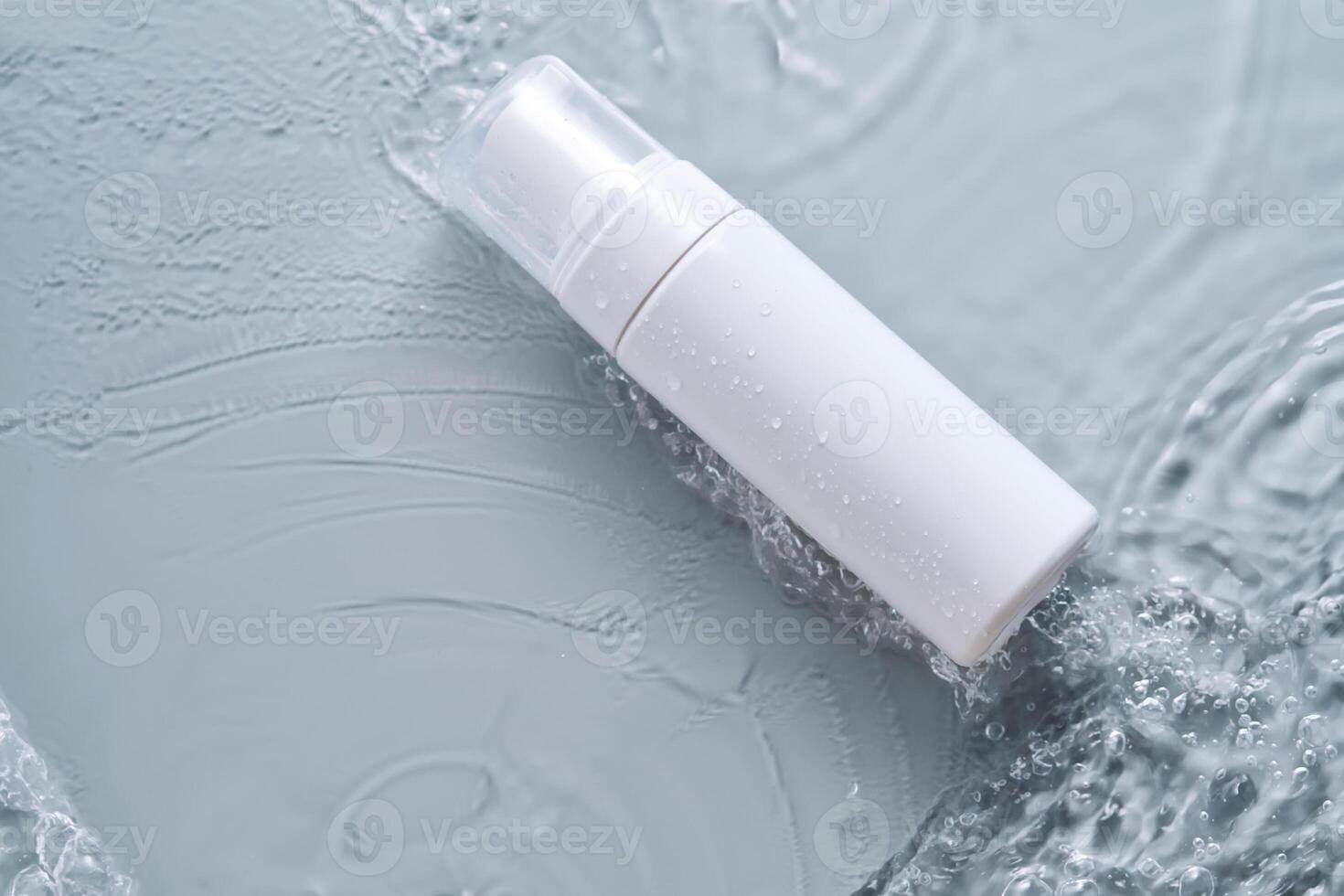Bottles of cosmetic products in water on a blue background. photo