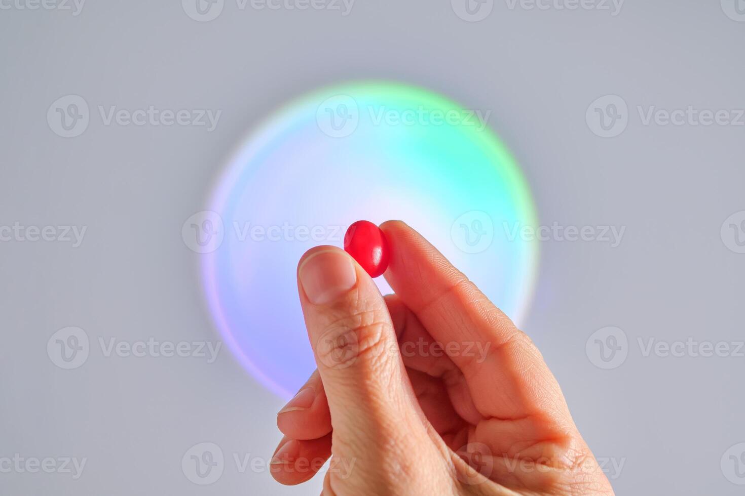 A red tablet of a vitamin complex in a hand. photo