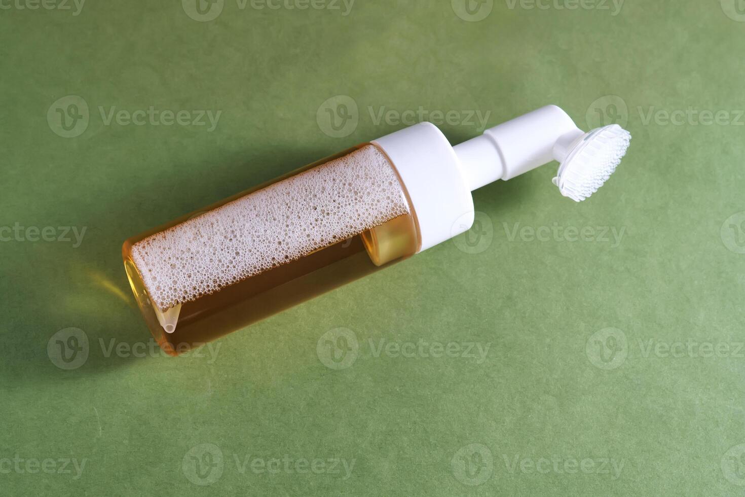 Beige facial foam with a dispenser and brush in a green background. photo