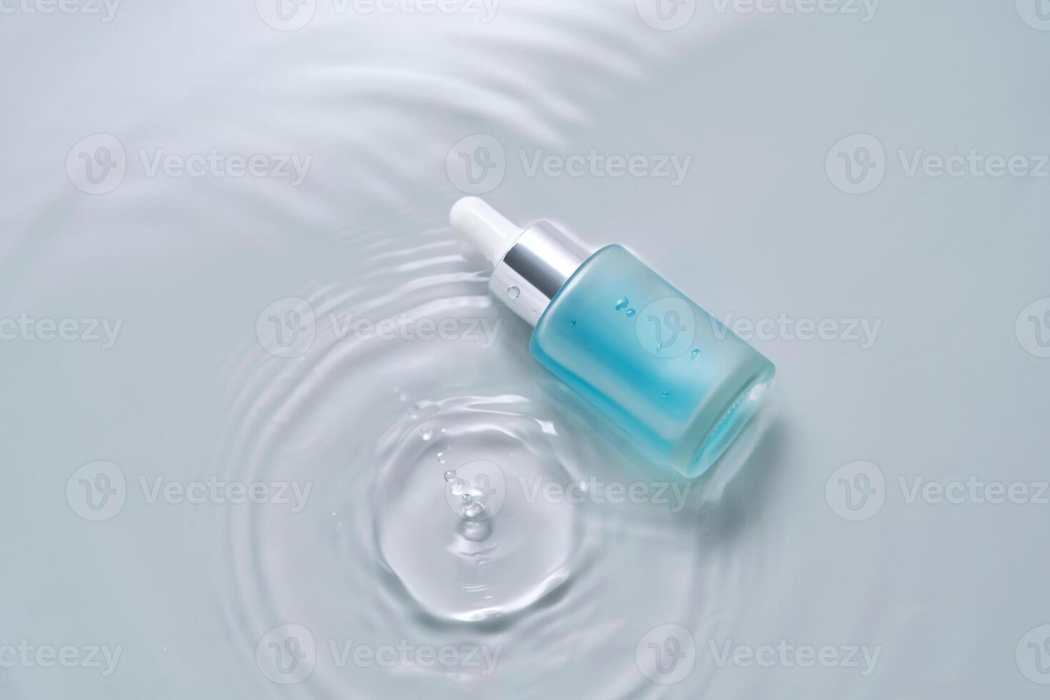 botellas de productos cosméticos con un cuentagotas en agua en un azul antecedentes. foto