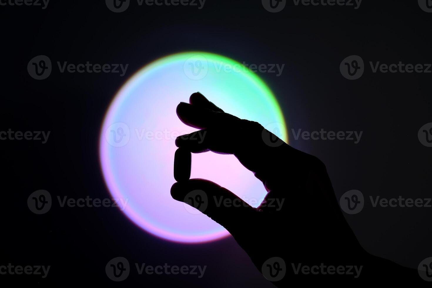 Tablet in hand against the background of a glowing circle. Silhouette. photo