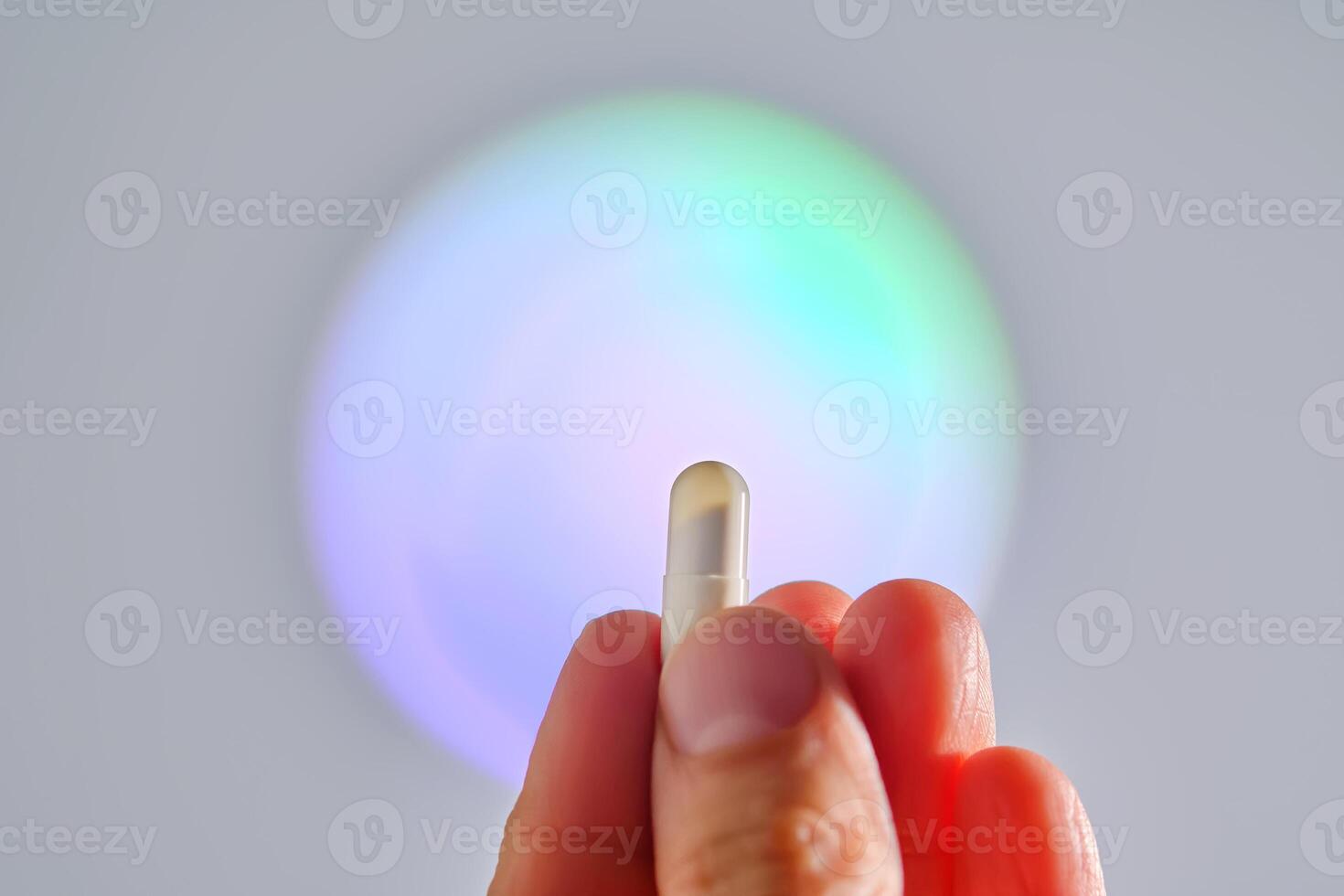 Capsule in hand against the background of a glowing circle. photo