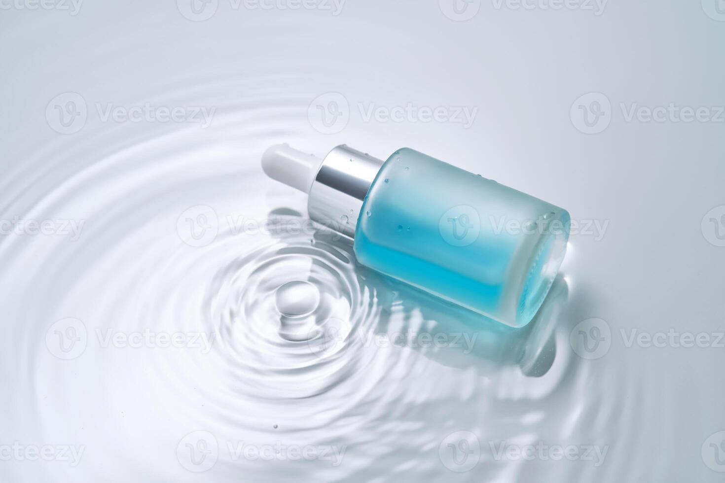 Bottles of cosmetics with a dropper in water on a blue background. photo