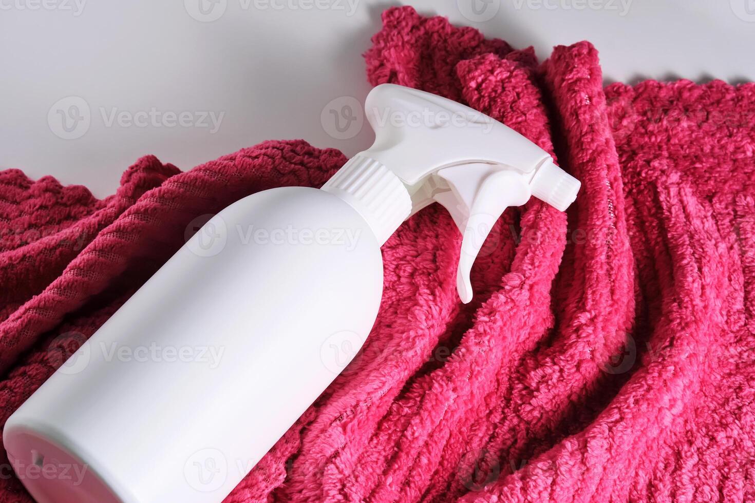 Cleaning product with a sprayer on a background of a red microfiber cloth. photo