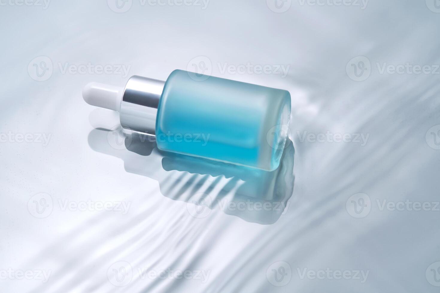 Bottles of cosmetics with a dropper in water on a blue background. photo