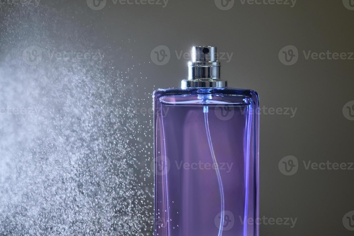 perfume rociar en un Violeta botella en un oscuro antecedentes. foto