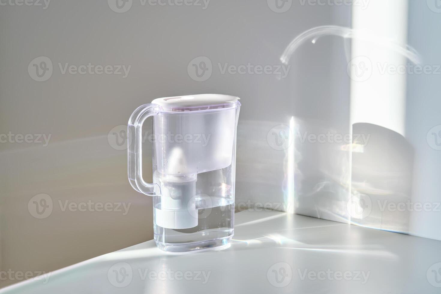 A jug with a water filter in the sun on the table. photo