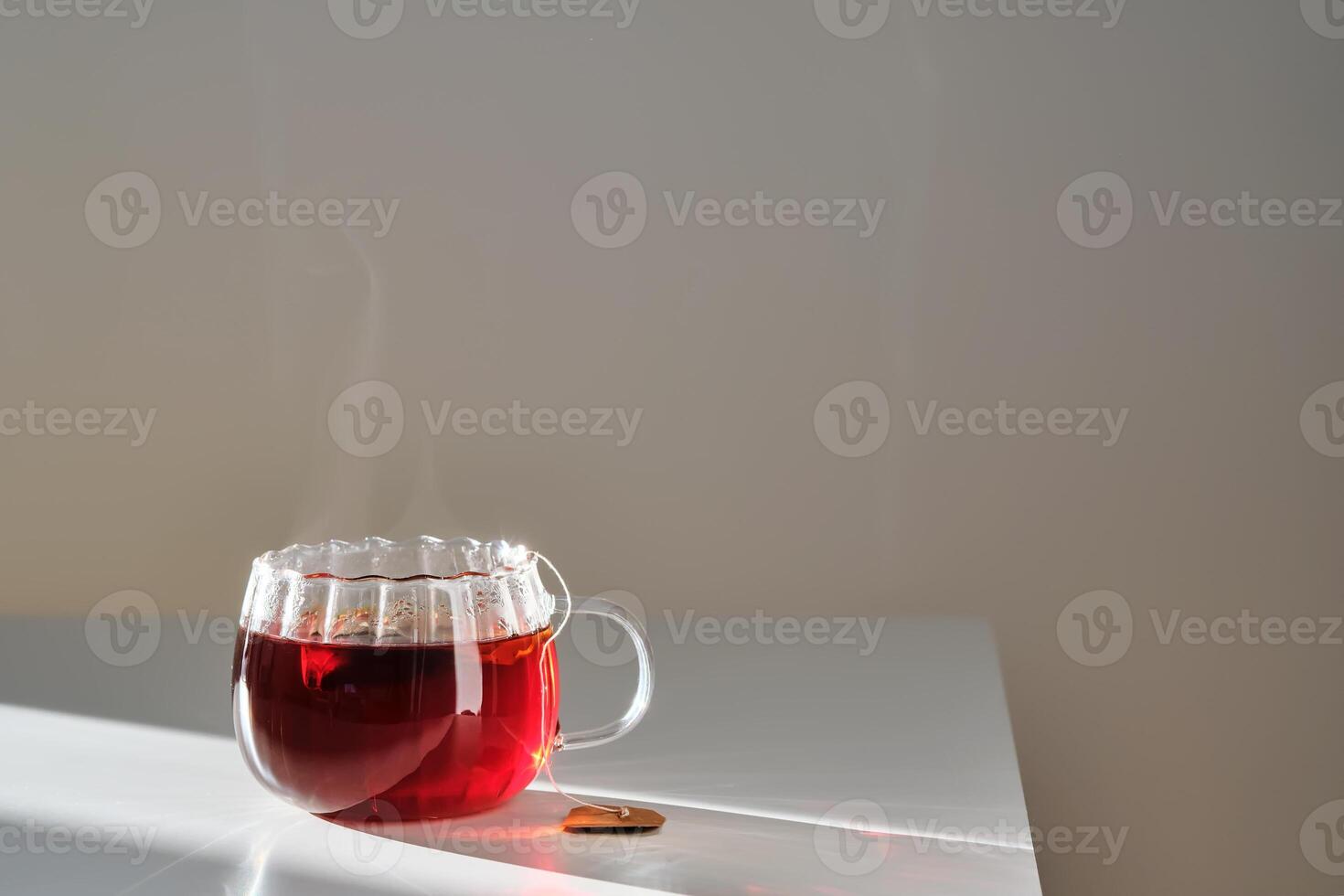 Glass mug with hot black tea on the table. photo