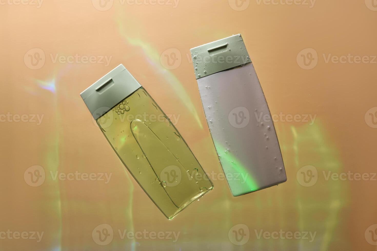Shampoo and hair conditioner in water on a beige background. View from below. photo