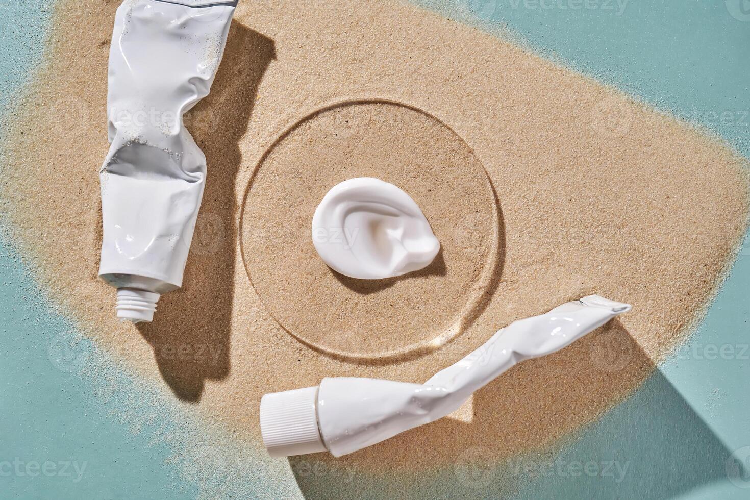 Two tubes of cream on the sand. photo