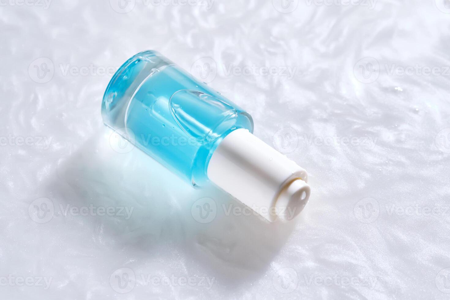 Bottles of serum with a dropper in liquid with pearl tints. photo