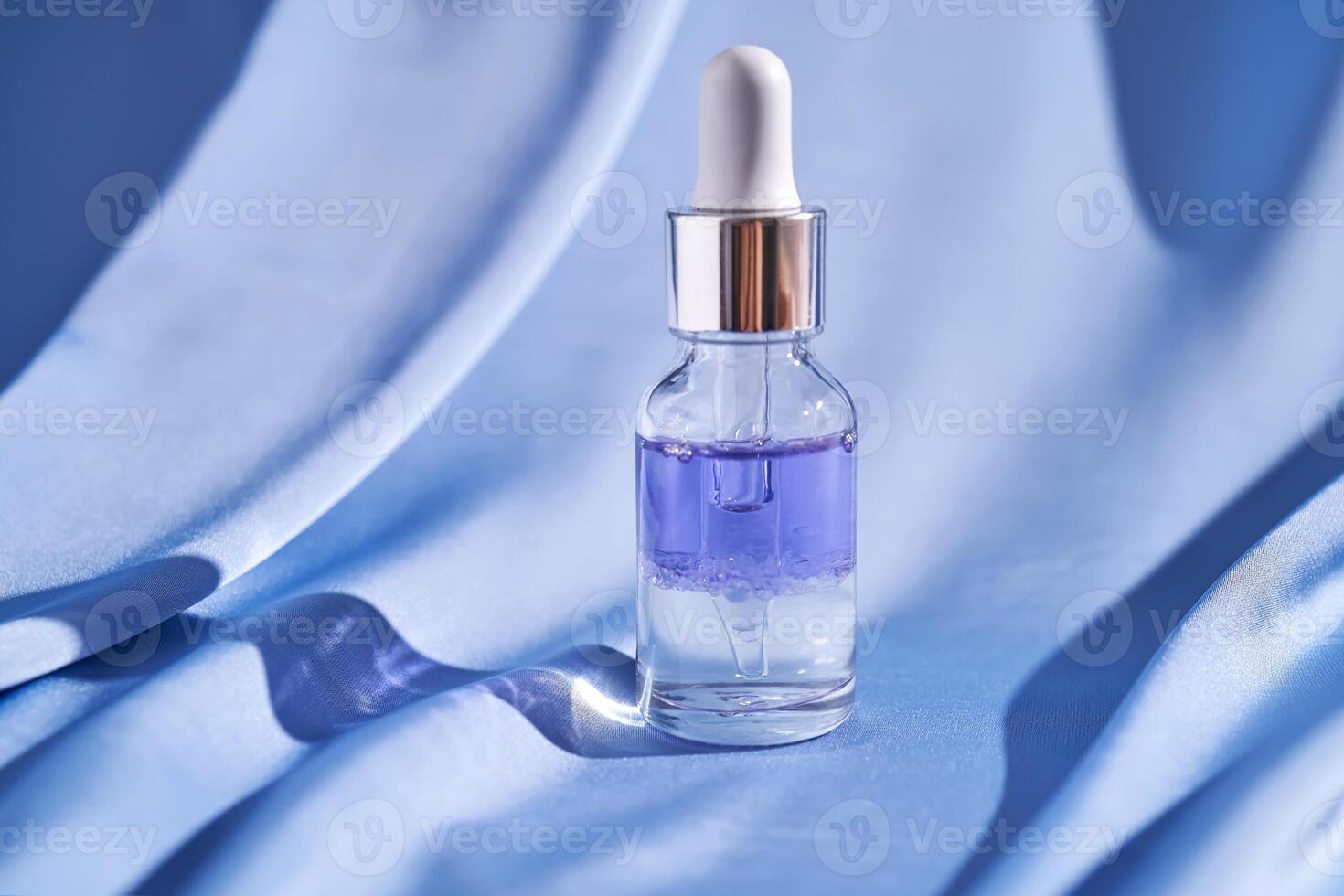 Two-component facial serum on a blue silk background. photo