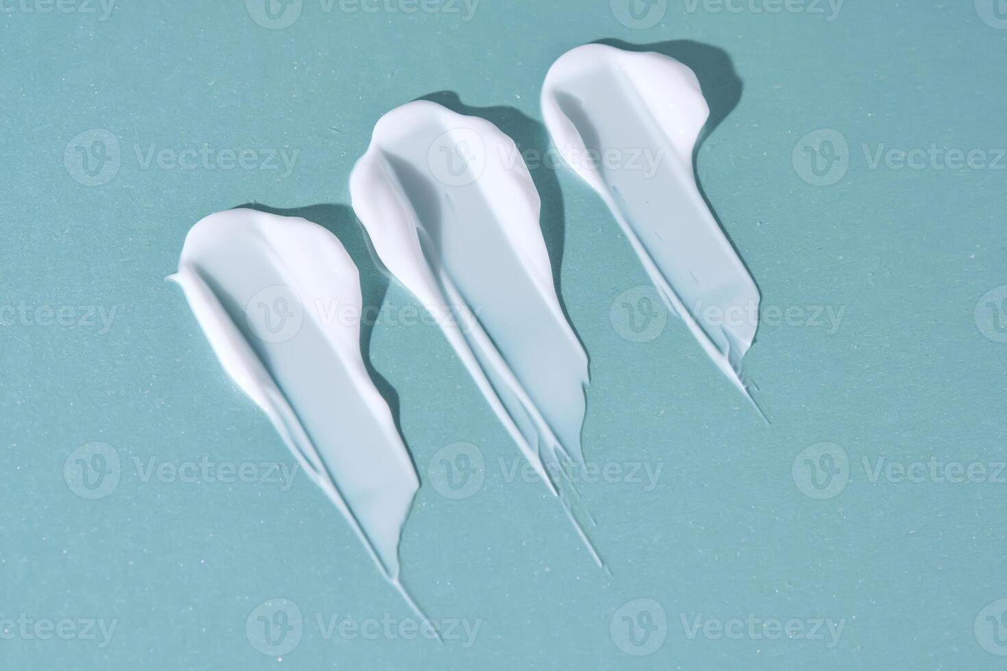 Three strokes of white cream on a blue background. photo