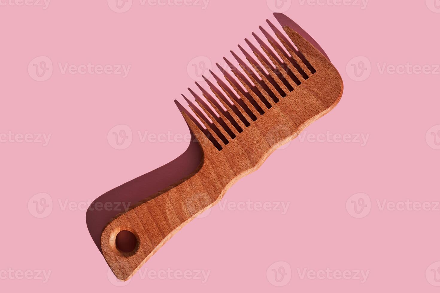 Wooden comb on a pink polka dot background. photo