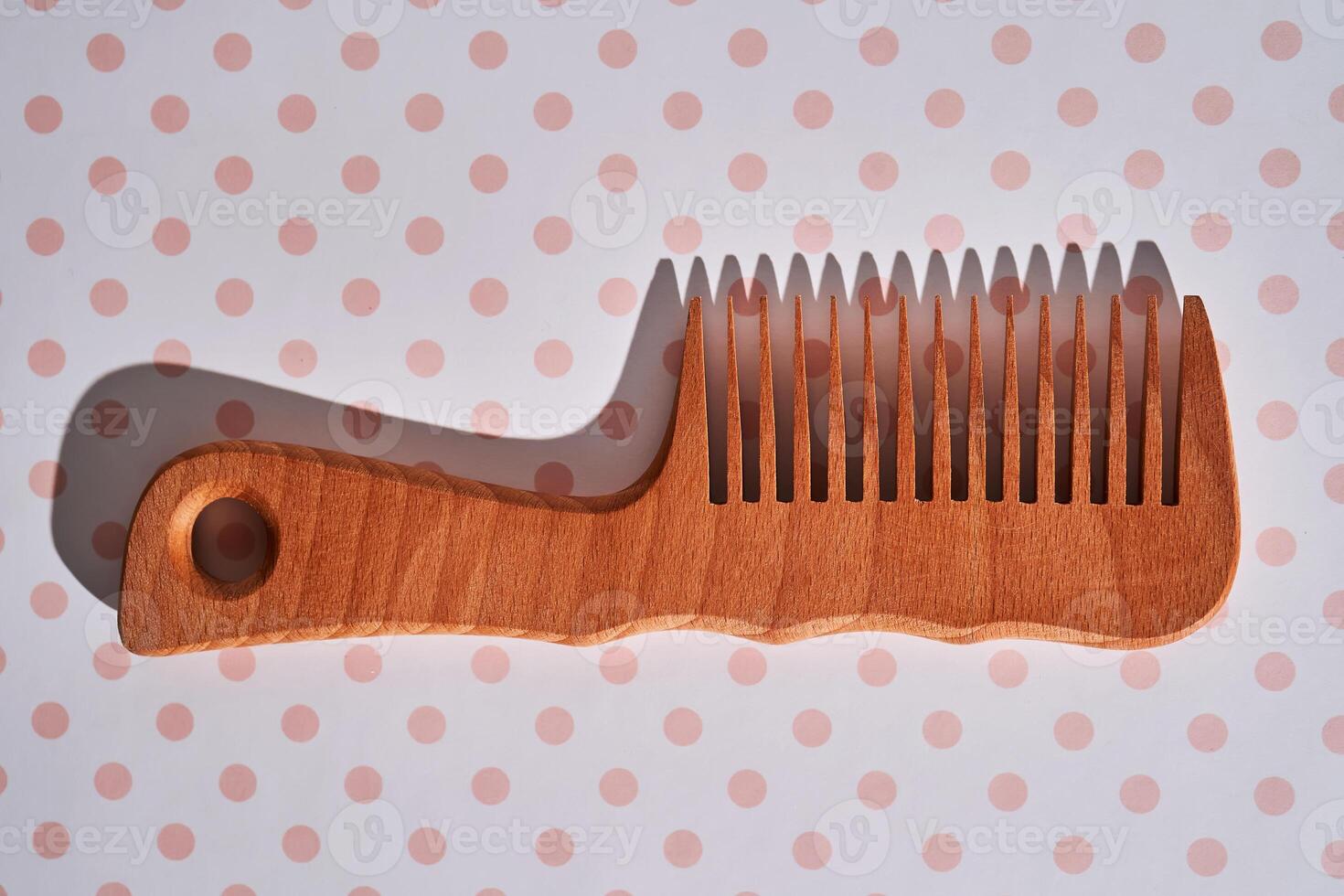 Wooden comb on a pink polka dot background. photo