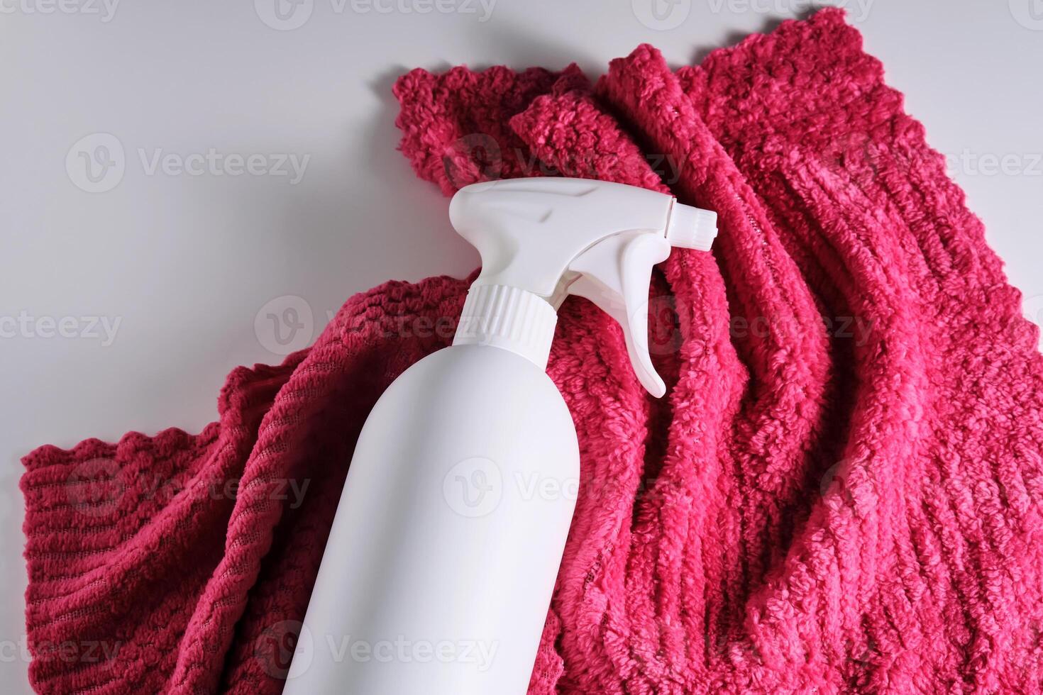 limpieza producto con un rociador en un antecedentes de un rojo microfibra paño. foto