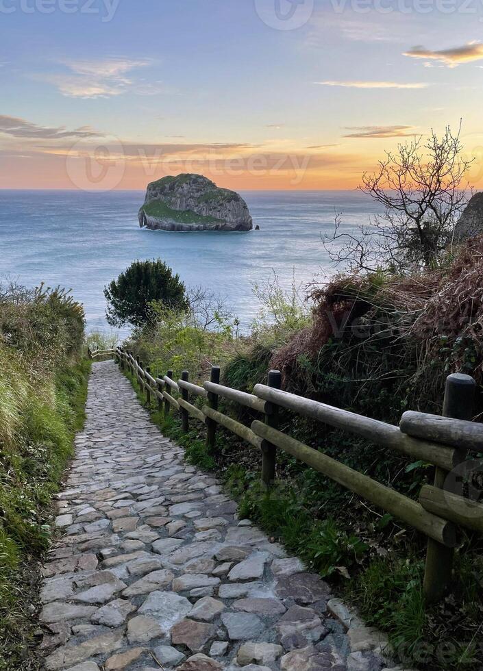 Path leading to the ocean at San Juan de Gaztelugatxe in Spain during sunrise photo
