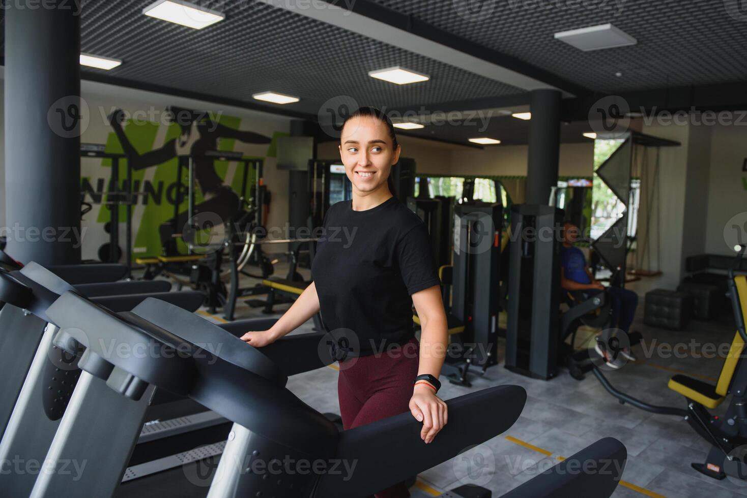 Attractive young sports woman is working out in gym. Doing cardio training on treadmill. Running on treadmill photo