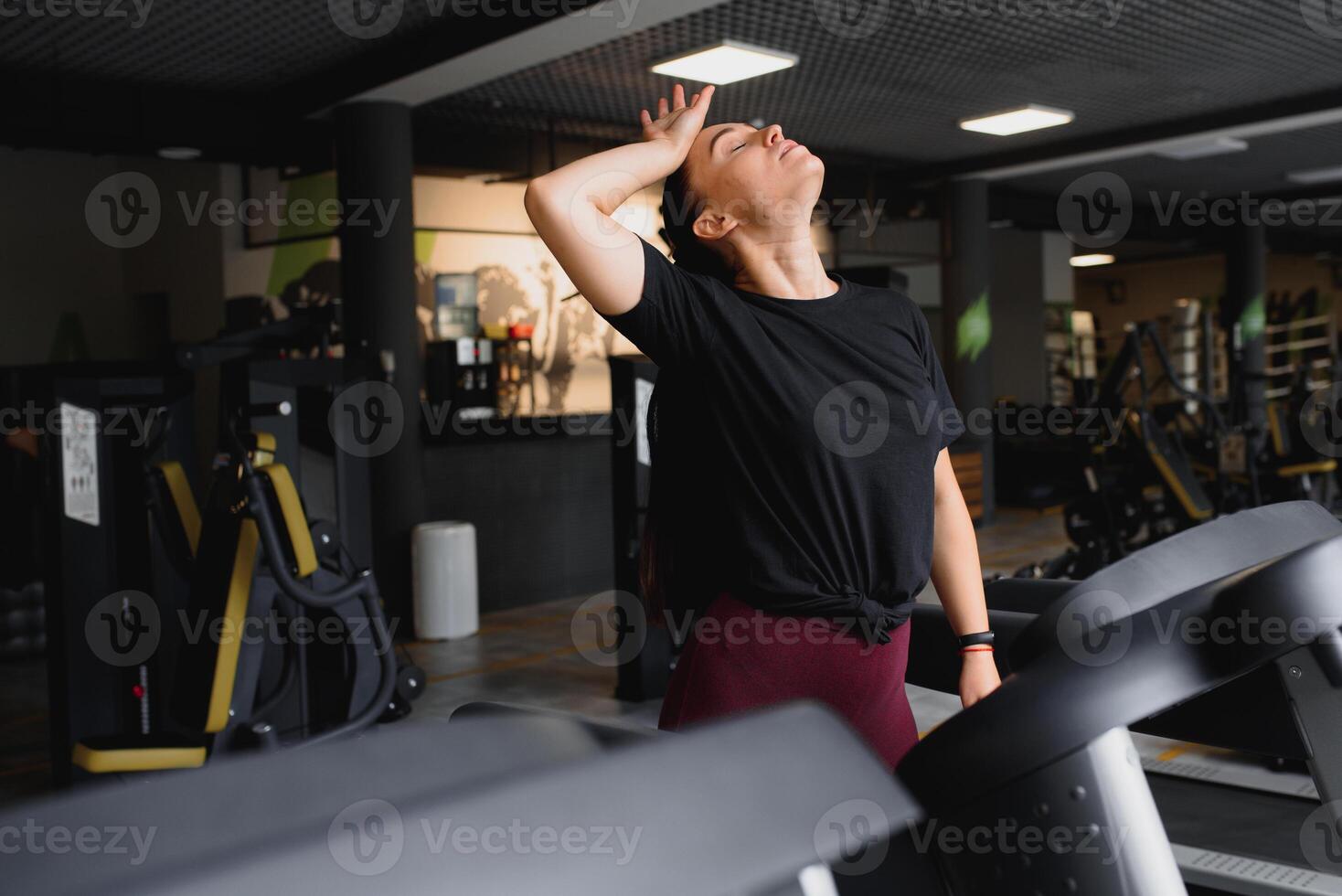 Portrait of a woman resting after her workout. She is leaning on a treadmill and looks completely exhuasted photo