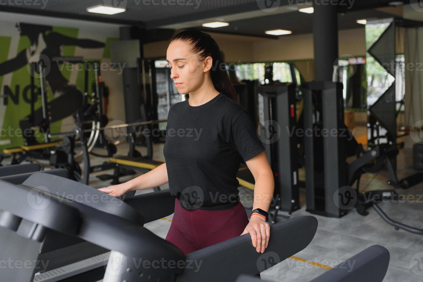 Attractive young sports woman is working out in gym. Doing cardio training on treadmill. Running on treadmill photo