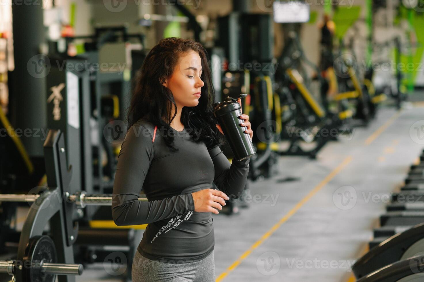 joven hermosa mujer Bebiendo agua en Deportes gimnasia. foto