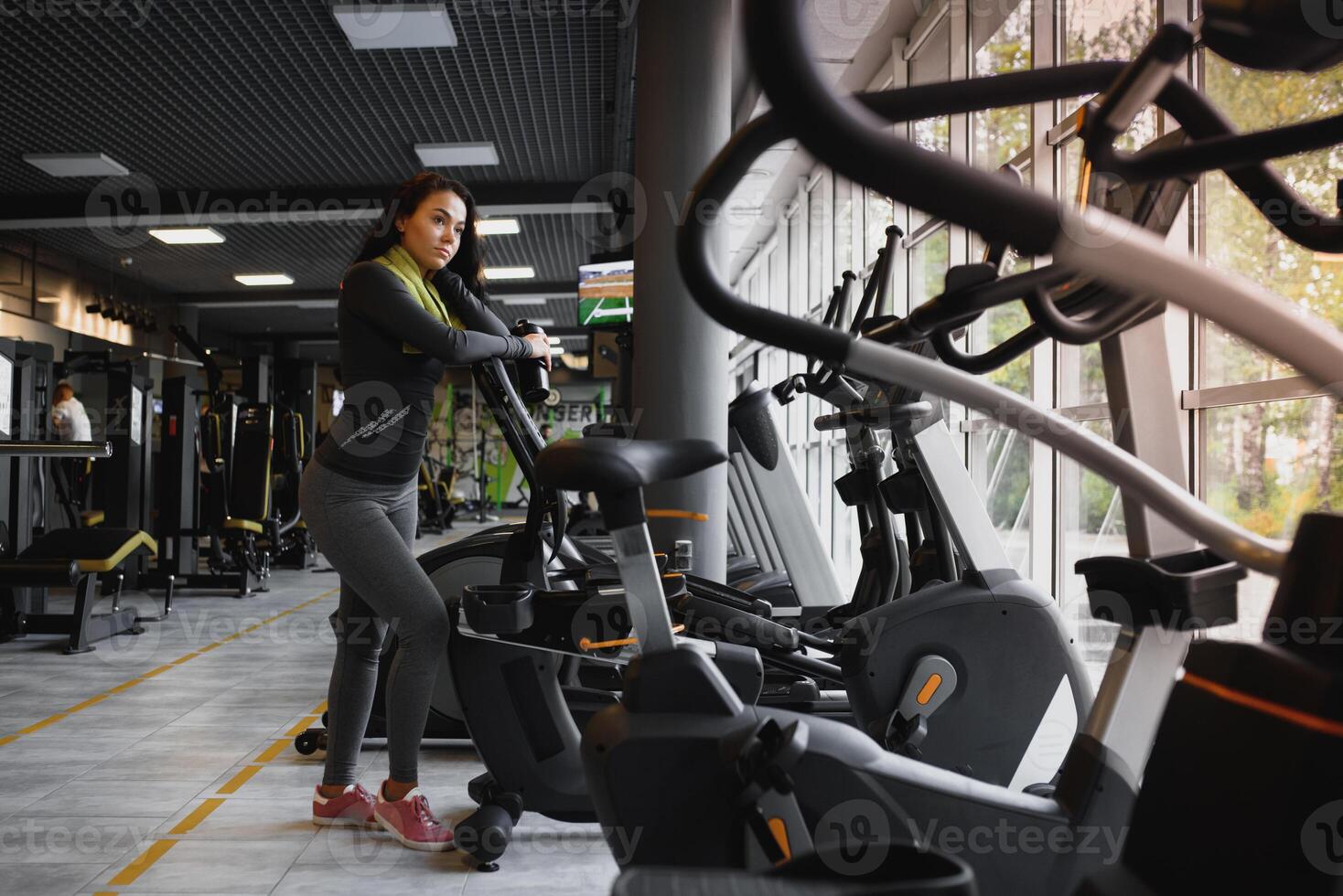 Young woman drinking water and taking a break after workout in gym photo