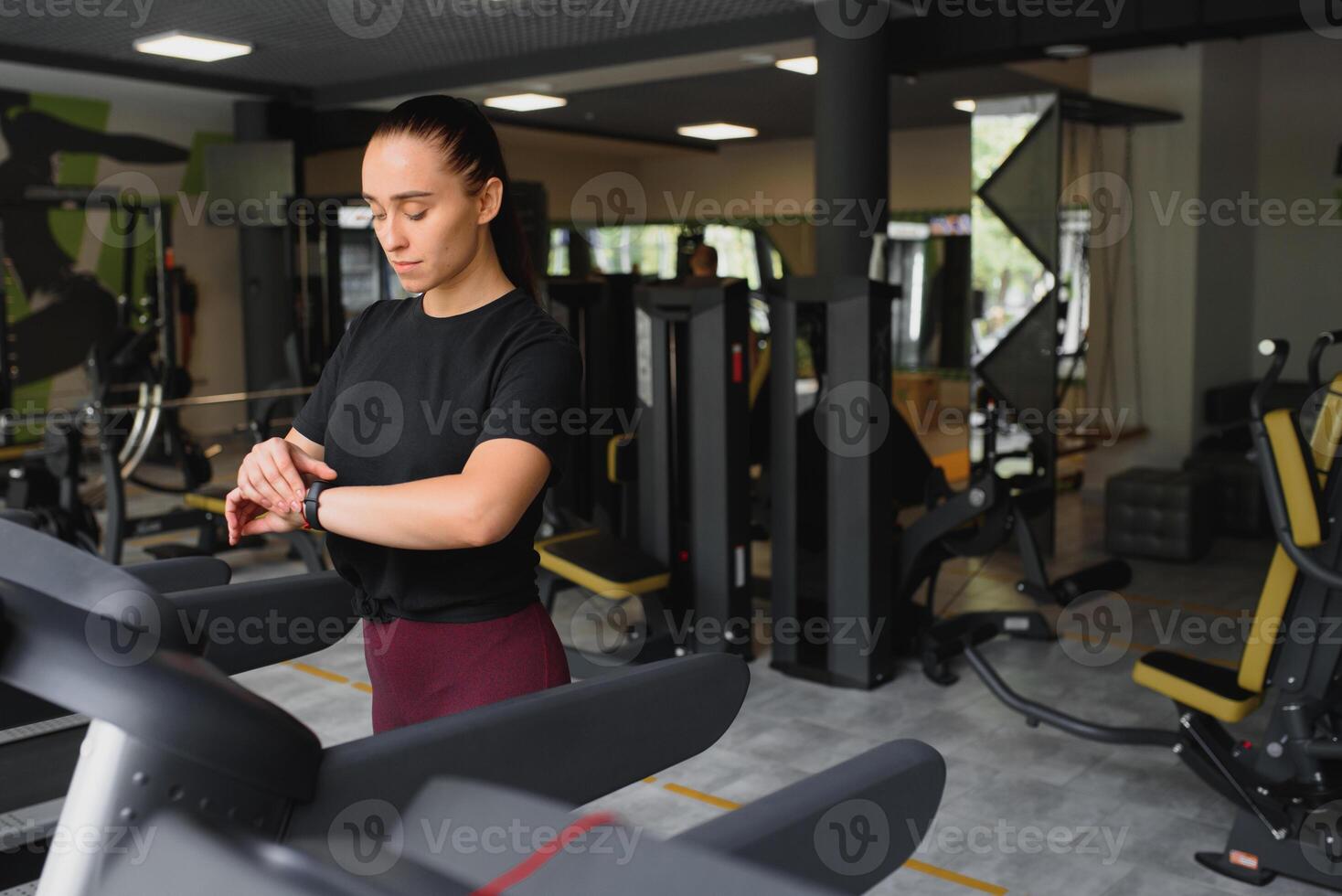 Attractive young sports woman is working out in gym. Doing cardio training on treadmill. Running on treadmill photo