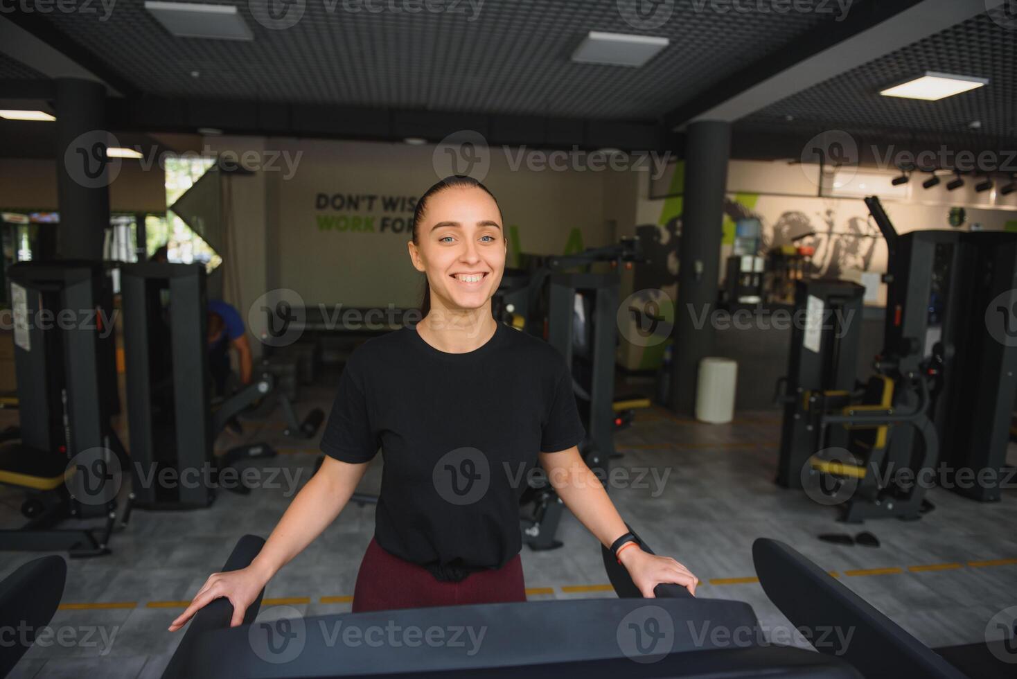 Woman trains on a treadmill in the gym. Young fitness girl running on treadmill machine. Sports exercises for weight loss photo