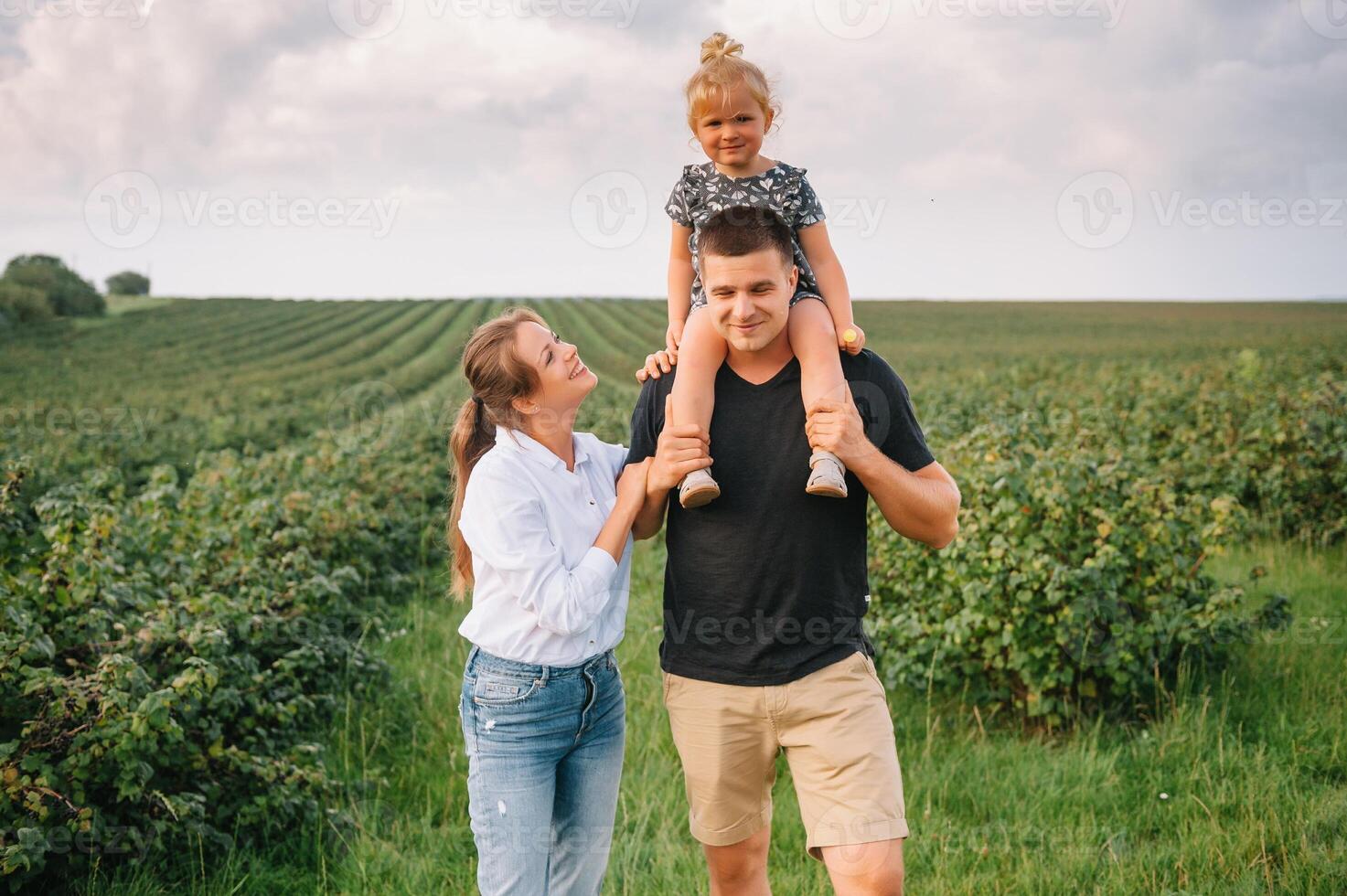 Happy family walking in the park. Mom, dad and daughter walk outdoors, parents holding the baby girl's hands. Childhood, parenthood, family bonds, marriage concept. photo