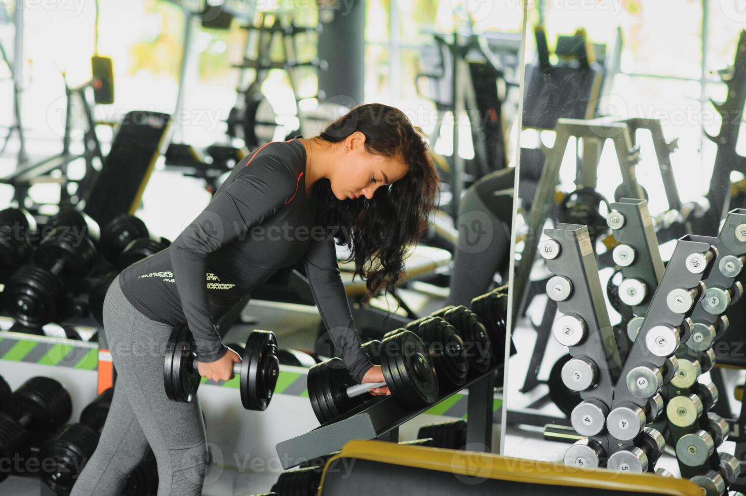 deportivo mujer en gimnasia. mujer levantamiento pesos y trabajando en su cofre a el gimnasia. foto