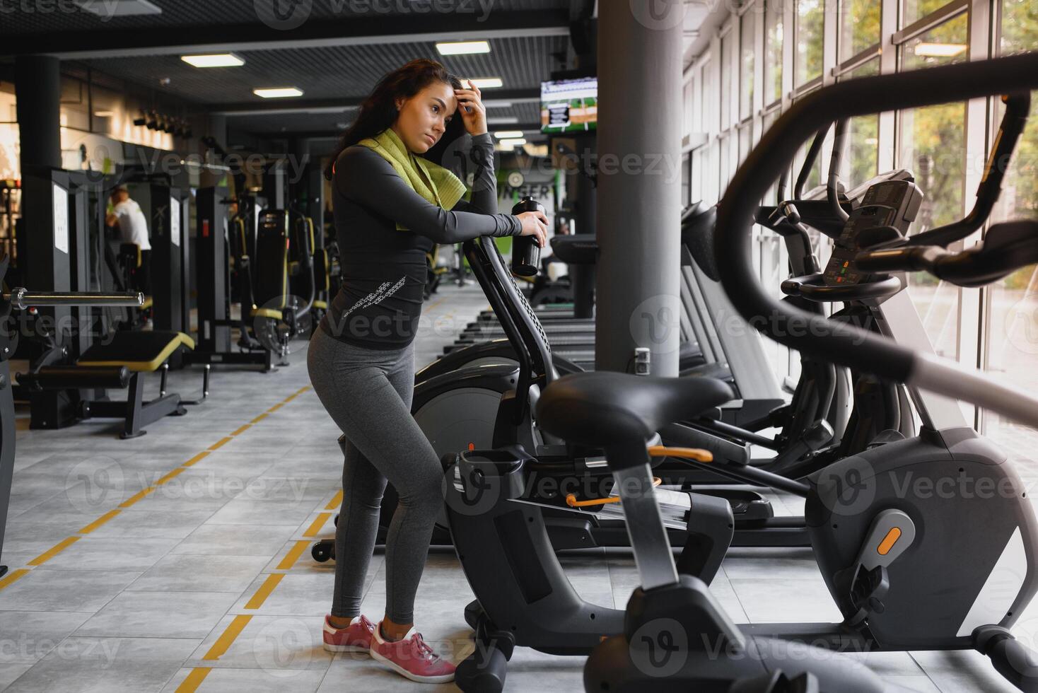 Young woman drinking water and taking a break after workout in gym photo